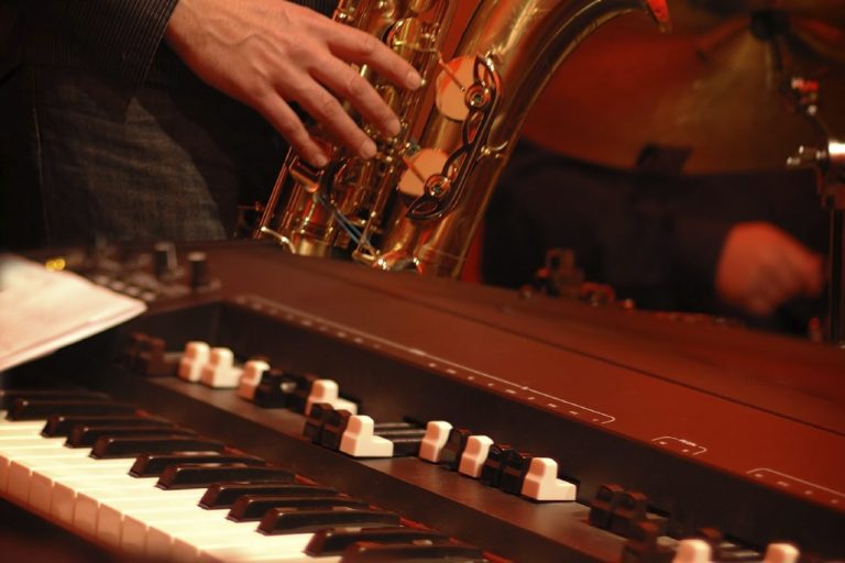 Ein Musiker spielt Saxophon, während ein anderes Instrument im Vordergrund sichtbar ist.