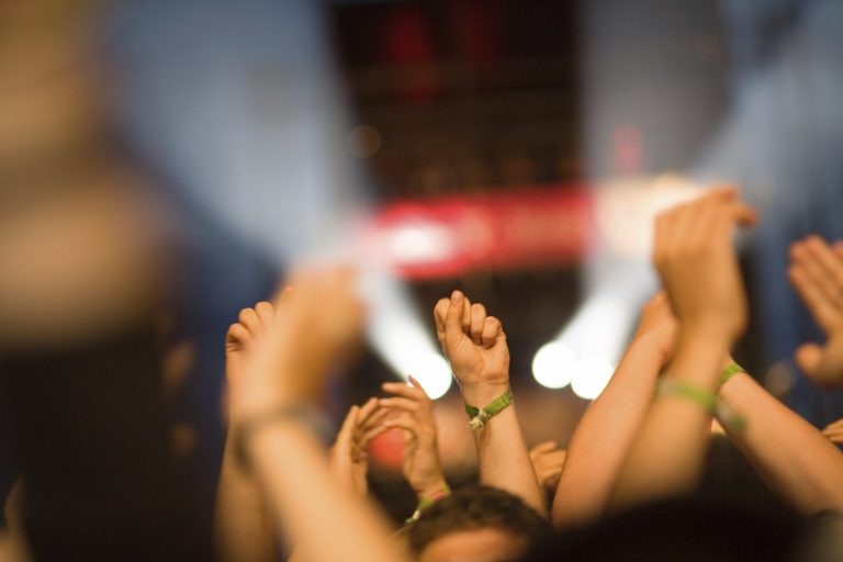 Hände erheben sich mit begeisterten Gesten bei einem Live-Konzert.