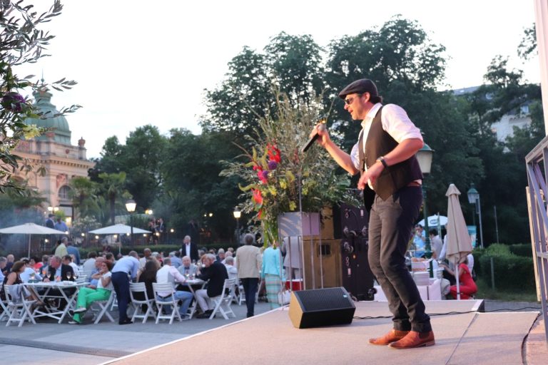 Entertainer singt auf einer Bühne vor einem Publikum in einem Park.